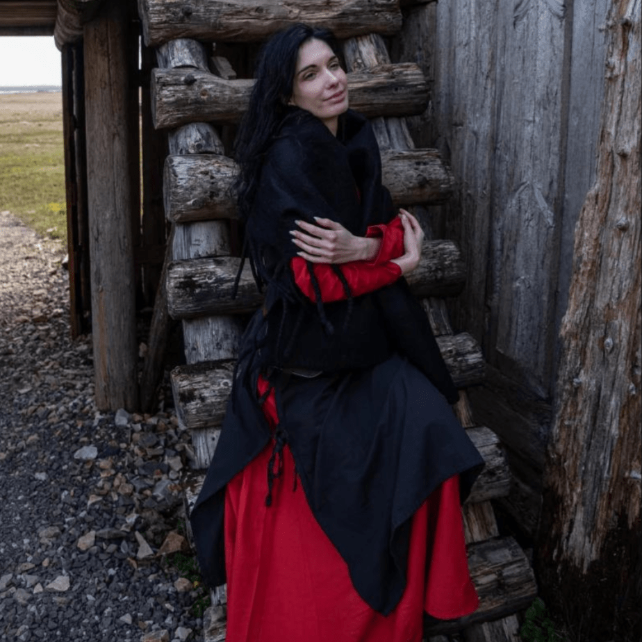Woman in a black wool Pirate stole with fringed edges, draped over a red dress.