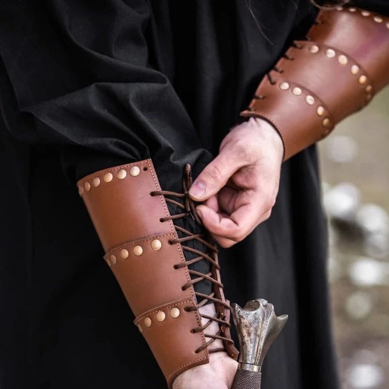 Brown leather Pirate arm bracer with bronze rivets and adjustable lacing on a person's forearm.