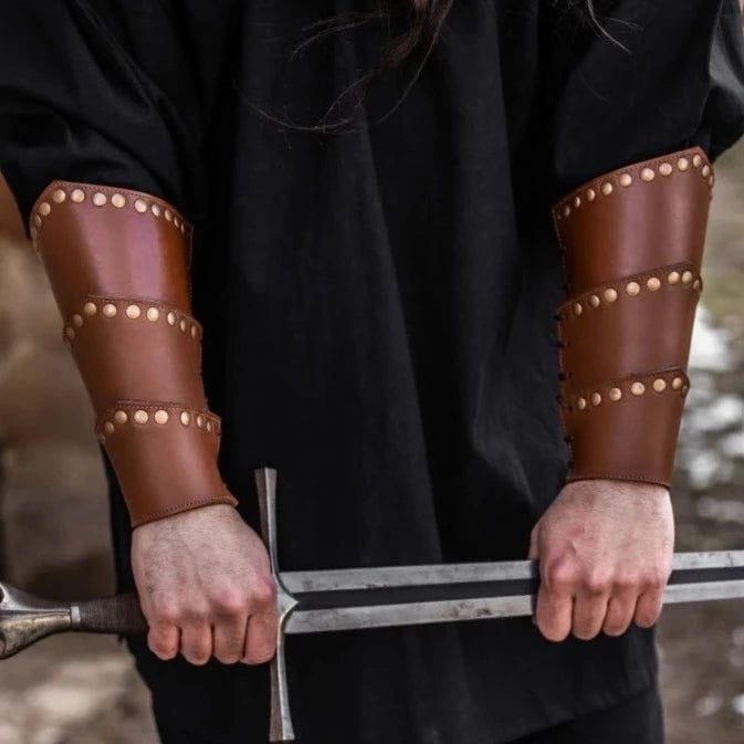 Brown leather Pirate arm bracers with bronze rivets and lacing, worn on forearms while holding a sword.