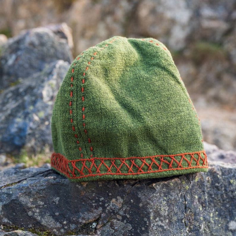 Green wool Pirate cap with distinctive orange Anders embroidery on a rocky background.