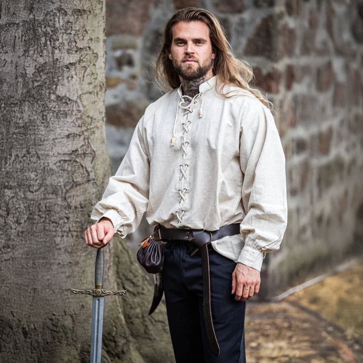 Man in a natural cotton-linen Pirate shirt with continuous cord lacing, wooden buttons, and tie sleeves.