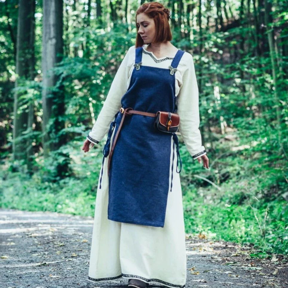 Pirate lady in a forest, wearing a narrow brown leather belt with a pouch over a blue dress.