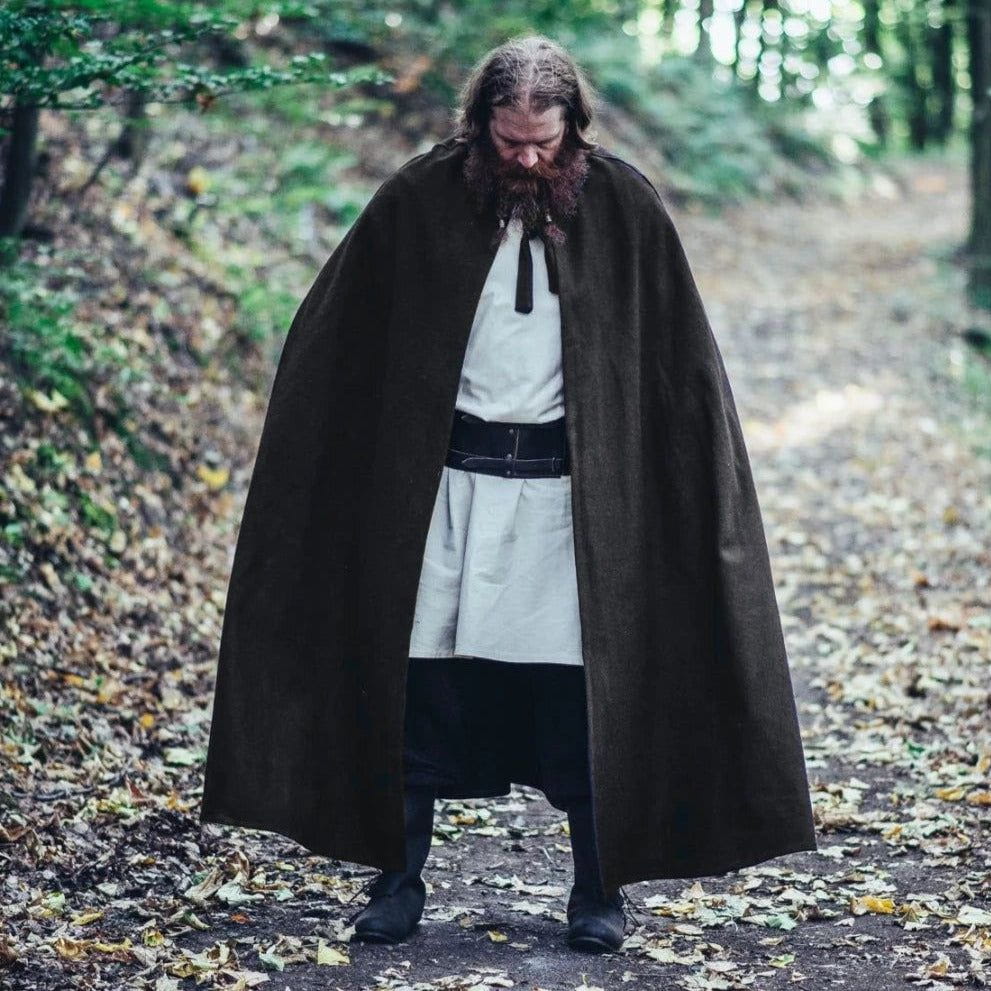 Man in a long, dark Pirate wool cloak with a dramatic hood and adjustable closure in a forest.