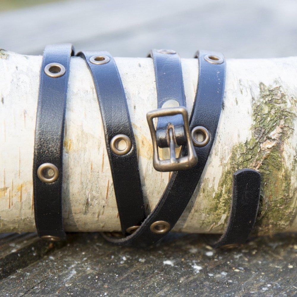 Black genuine leather multistrap Pirate bracelet with brass buckle and eyelets, wrapped around a birch log.