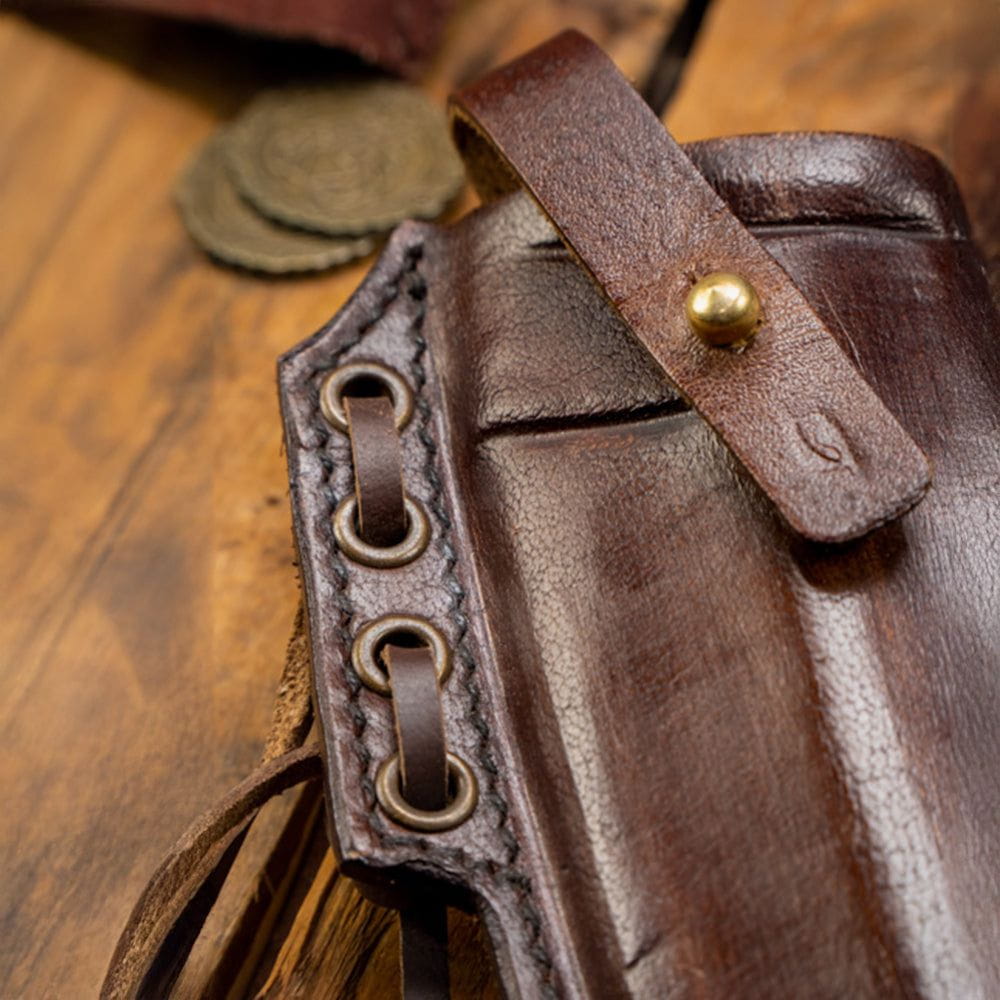 Close-up of a brown leather Pirate scabbard with brass hardware and belt loops on a wooden surface.