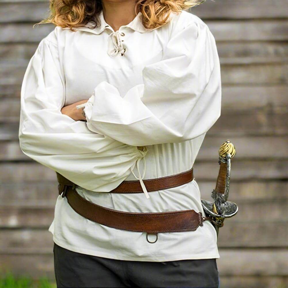 Pirate brown leather sword belt with brass buckles worn over a white shirt, holding a sword.