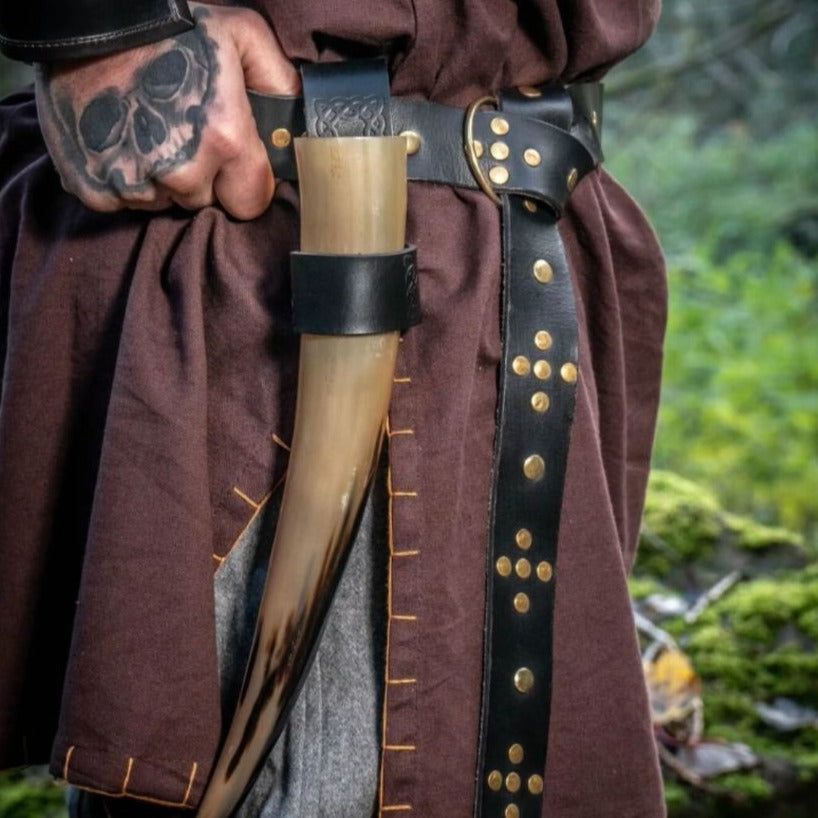 Black riveted Pirate leather belt with gold studs, ring loop, and horn holder on a brown tunic.