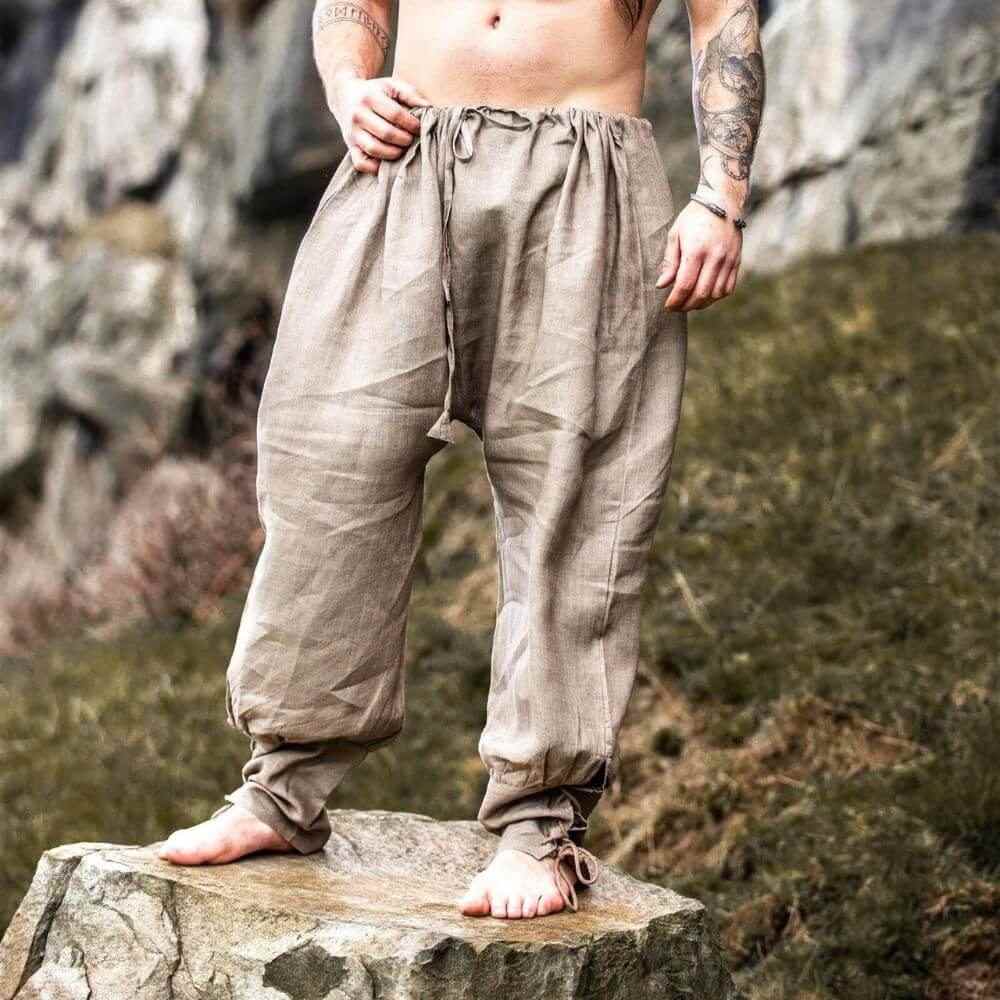 Stone color linen Pirate pants with drawstring waist and lace-up tapered legs, worn by a person standing on a rock.