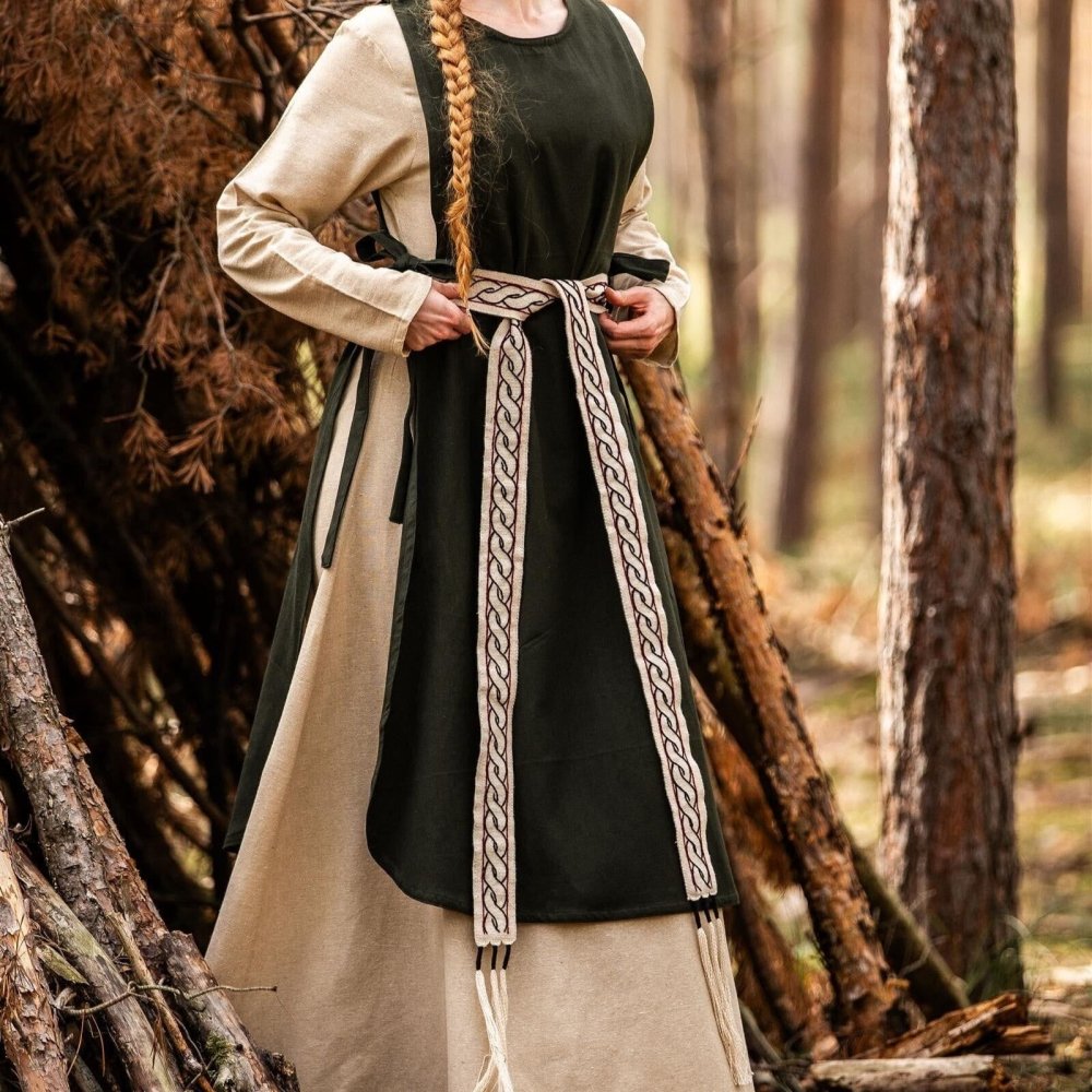 Pirate costume featuring a woman in a dark green and beige dress, tying a decorative woven belt.