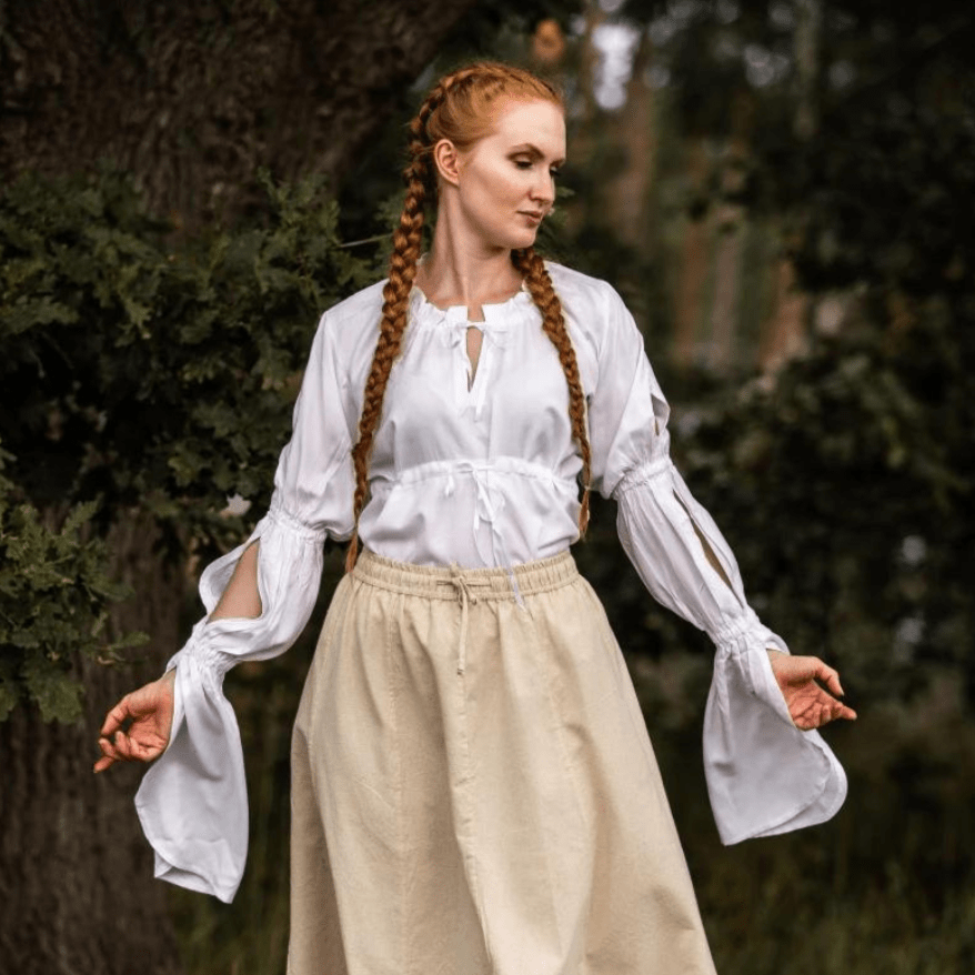 White long-sleeve Pirate blouse with ruched sleeves and adjustable waist lacing, worn with a beige skirt.