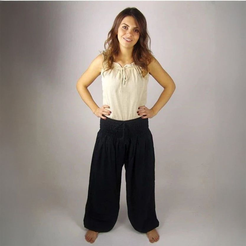 Woman in black high-waist, wide-leg viscose Pirate pants with ankle cuffs and an elastic drawstring waist.