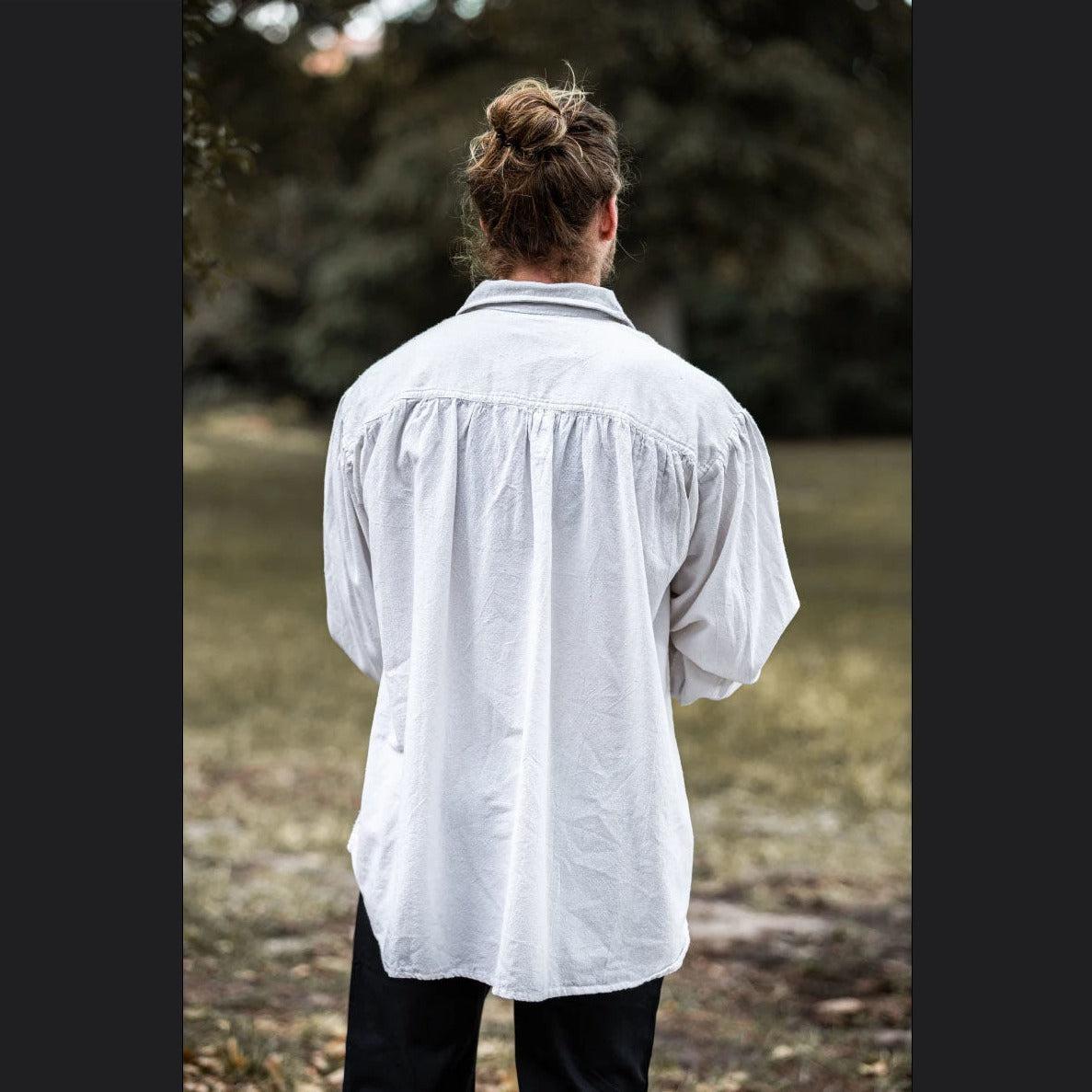 Back view of a man wearing a loose-fitting white cotton Pirate shirt with a classic V-neck and turned collar.