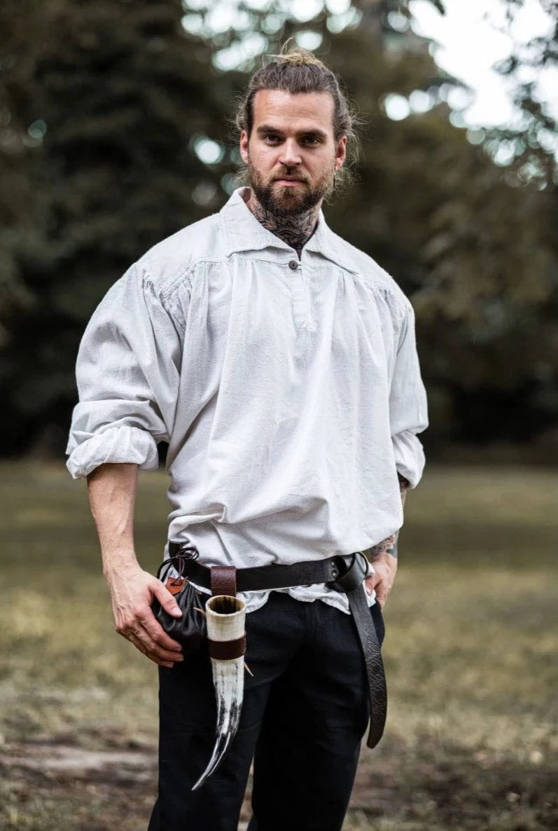 Man in a loose-fitting white cotton Pirate shirt with wooden buttons, V-neck, and rolled sleeves.