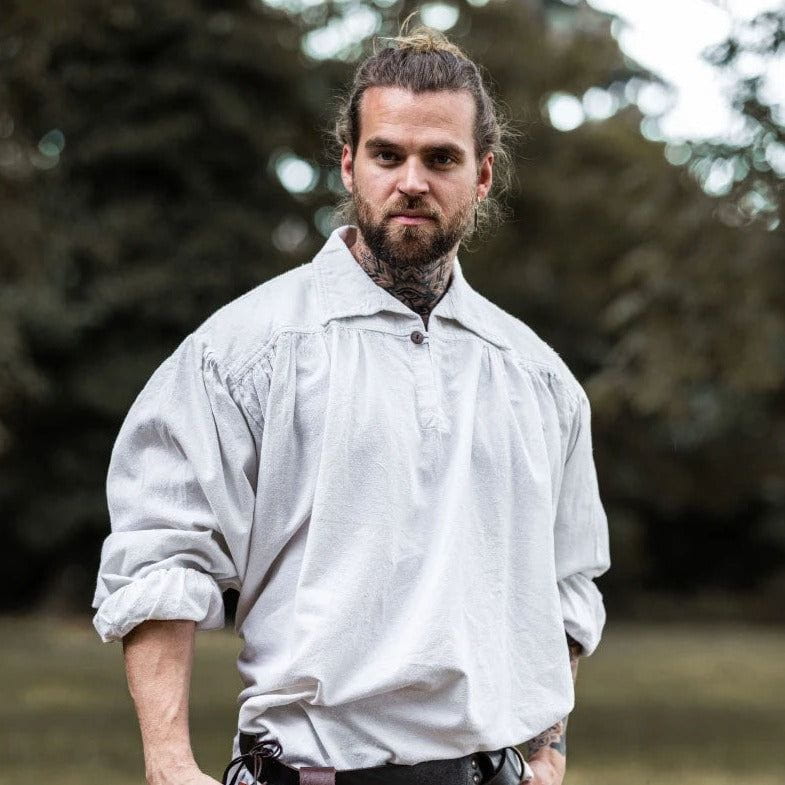 Man wearing a loose-fitting white cotton Pirate shirt with a V-neck, turned collar, and wooden button.