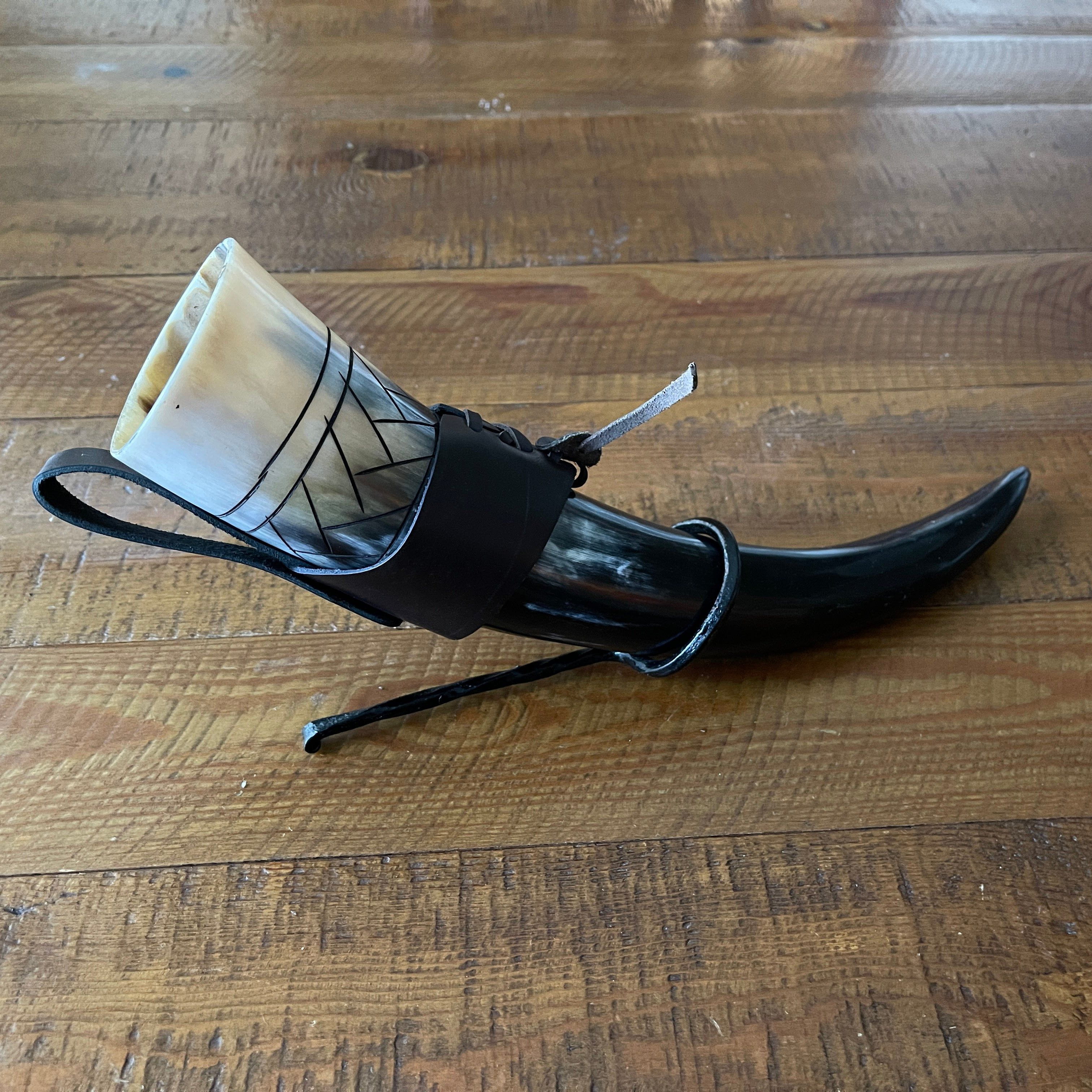 Pirate drinking horn, 12-14" natural horn with scale carving, black leather belt loop, on wood.