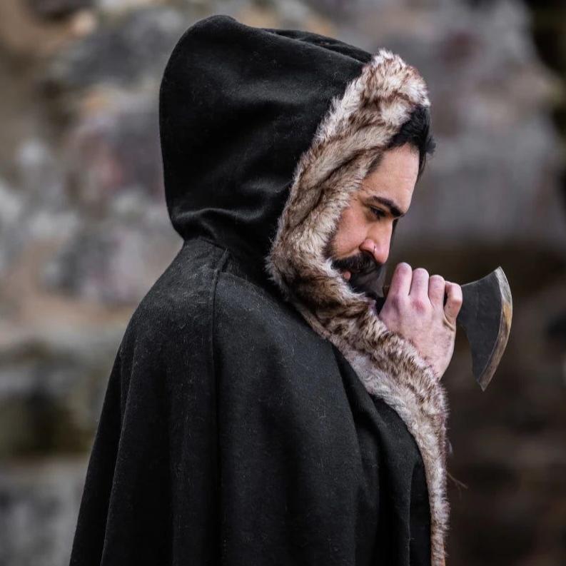 Pirate in a black wool hooded cape with luxurious faux fur trim, holding an axe.