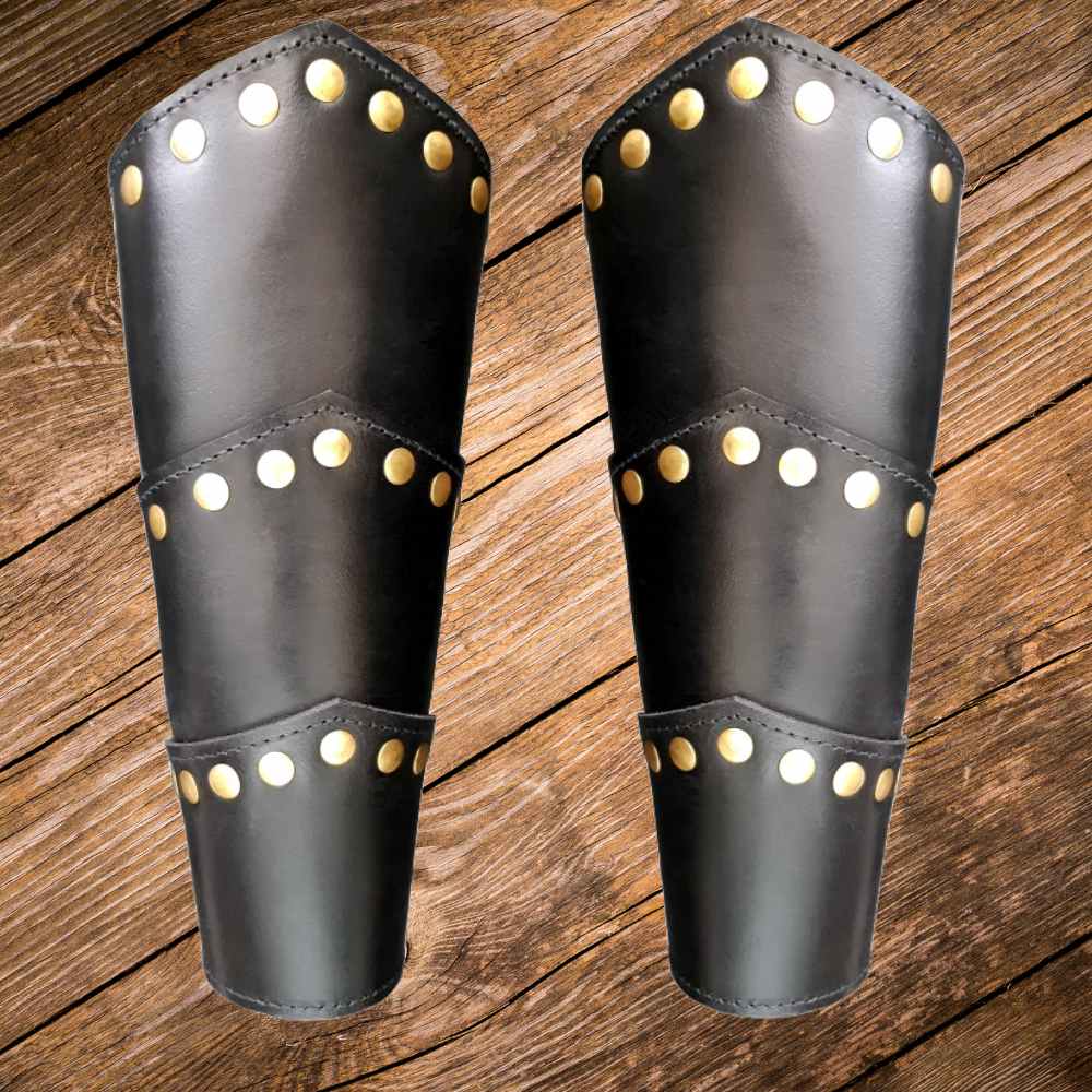 Pair of black leather Pirate arm bracers with gold rivets, 9.4 inches tall, on a wooden background.