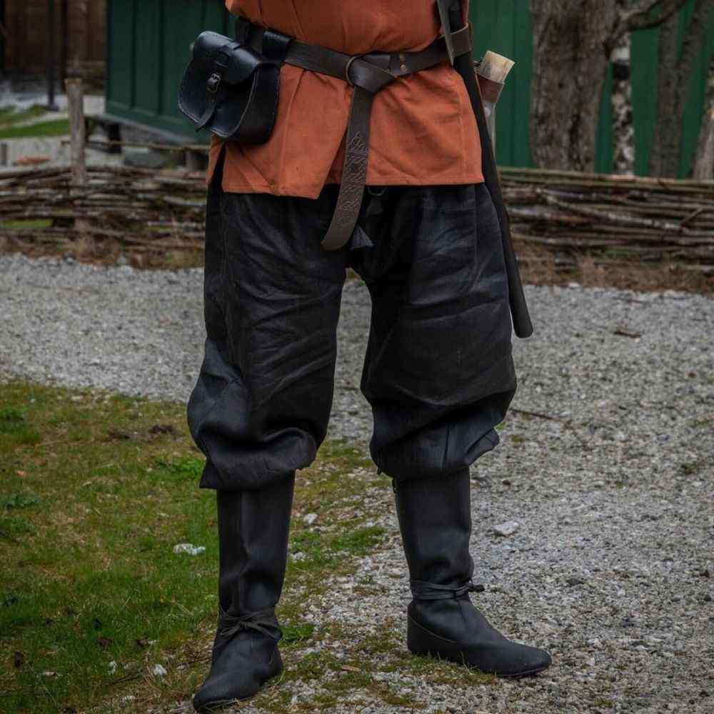 Black linen Pirate pants with tapered legs and lace-up closures, worn with boots and an orange tunic.