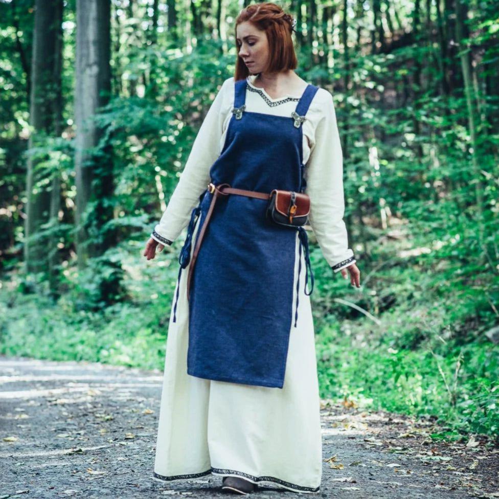 Blue cotton Pirate overdress with wide straps and side ties, worn over a cream underdress in a forest.