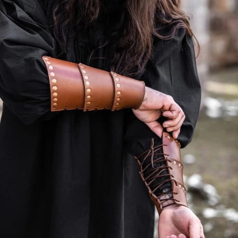 Brown leather Pirate arm bracer with bronze rivets and adjustable lacing on a person's forearm.