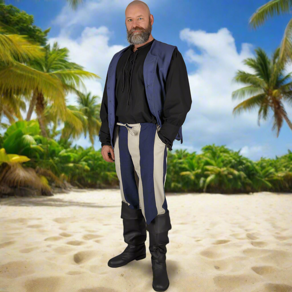 Man in classic striped pirate pants and black boots poses on sandy beach, styled with Viking shoes and handmade leather boots.