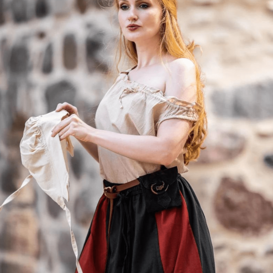 Woman in a beige top and red/black skirt holding a natural cotton Pirate coif.