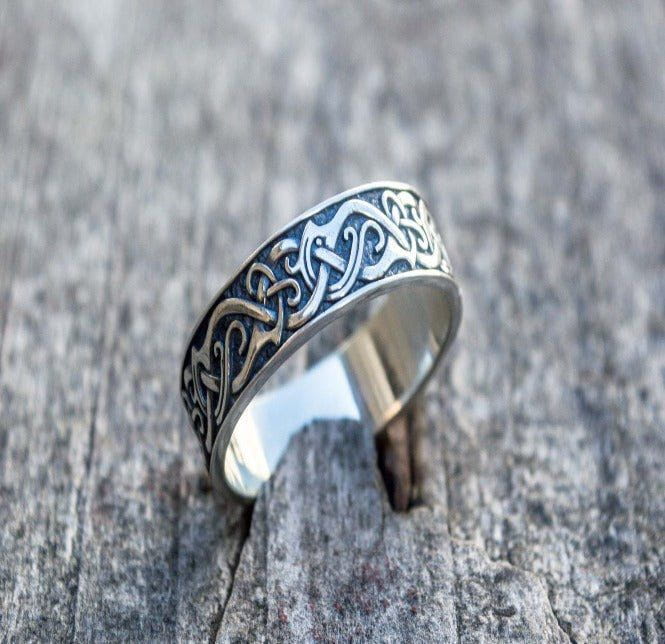 Handcrafted sterling silver Pirate ring with dark, intricate Celtic knotwork on a weathered wood surface.