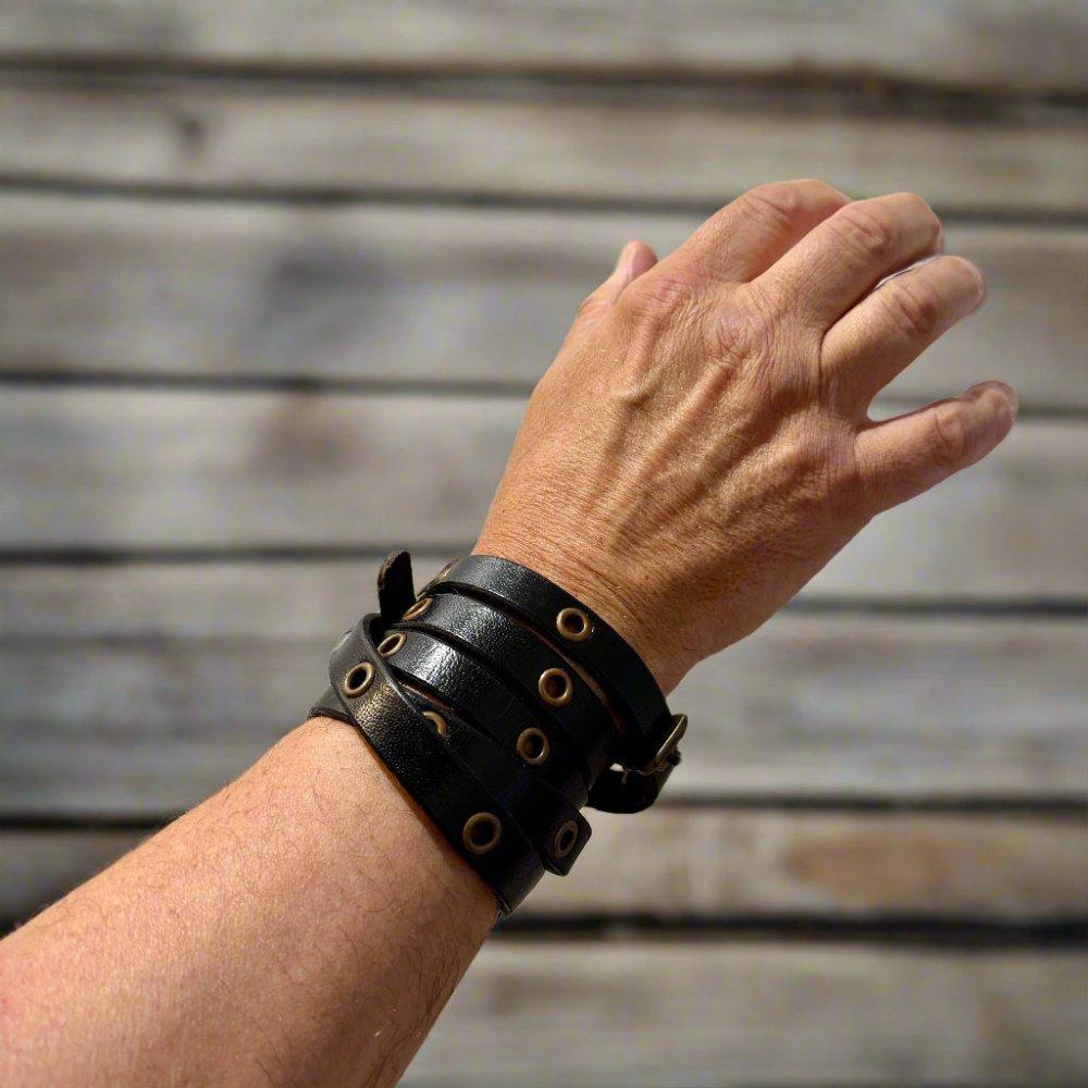 Black genuine leather multistrap Pirate bracelet with brass hardware and adjustable closure on a wrist.