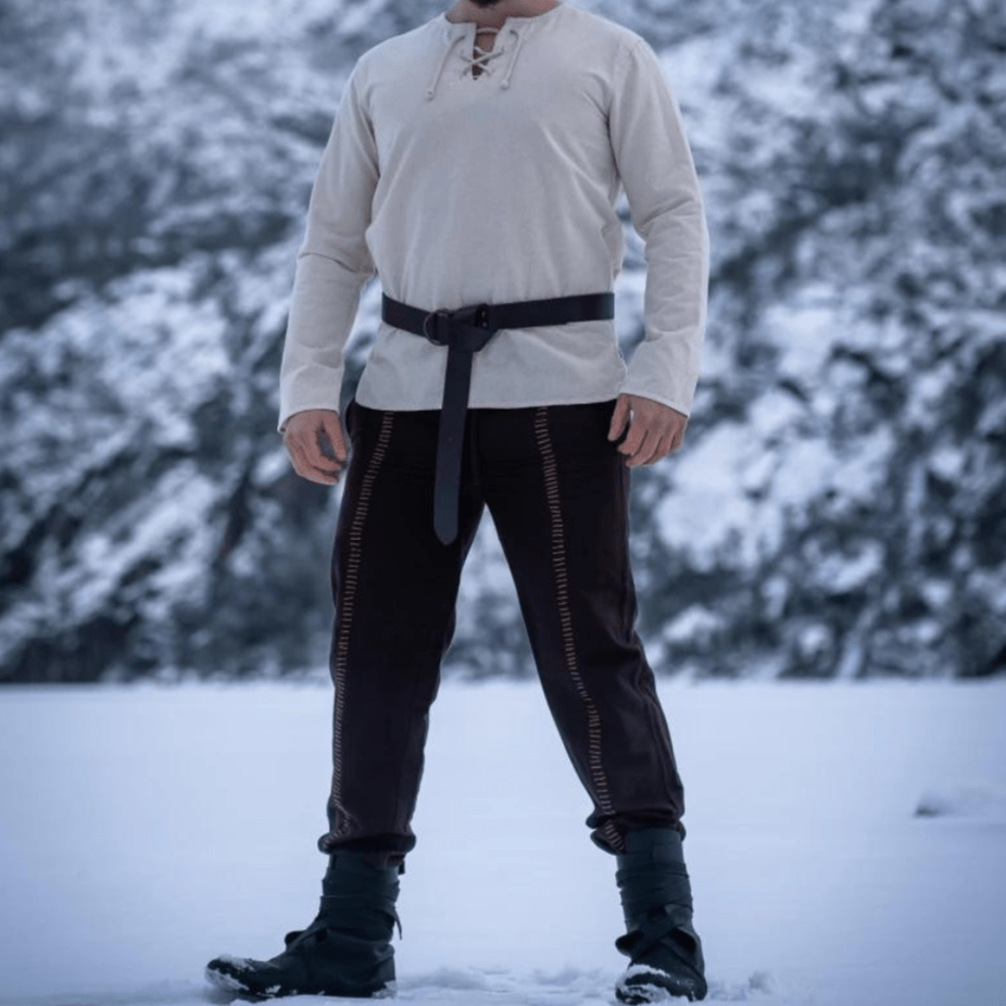 Natural cotton long-sleeve Pirate tunic with lace-up collar, paired with black pants and belt in snow.