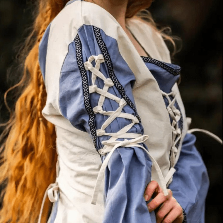 Natural and blue Pirate cotton gown with laced cuffs, V-neck, and open trumpet sleeves.