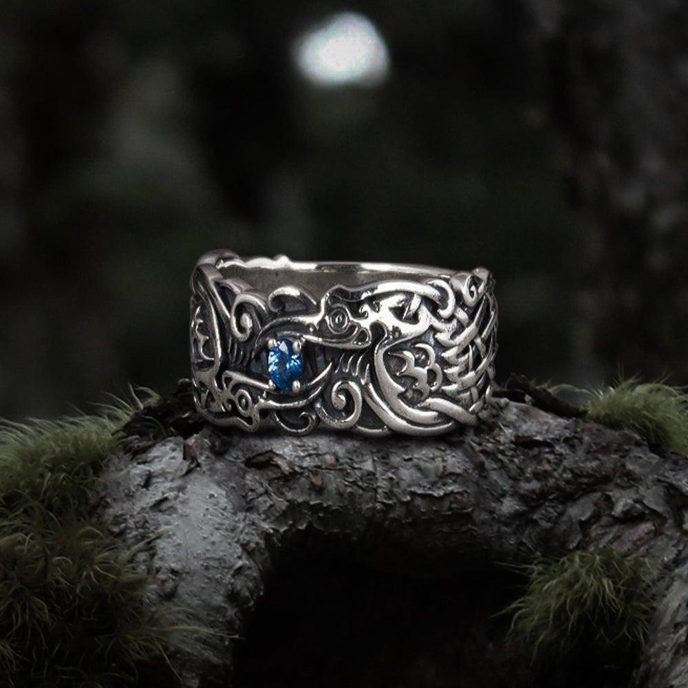Sterling silver Pirate ring with detailed Odin's ravens and a blue gemstone, on a mossy branch.
