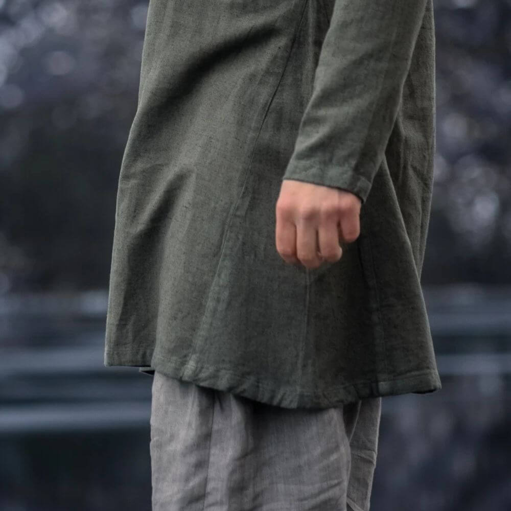 Olive green hand-woven linen Pirate tunic, thigh-length with classic neckline, worn over grey trousers.
