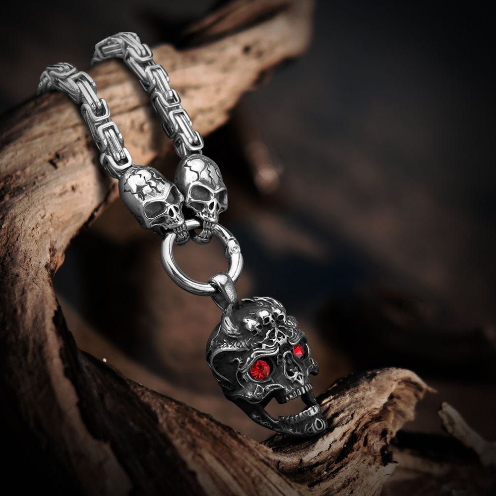 Stainless steel Pirate skull pendant with red crystal eyes on a square chain, resting on wood.