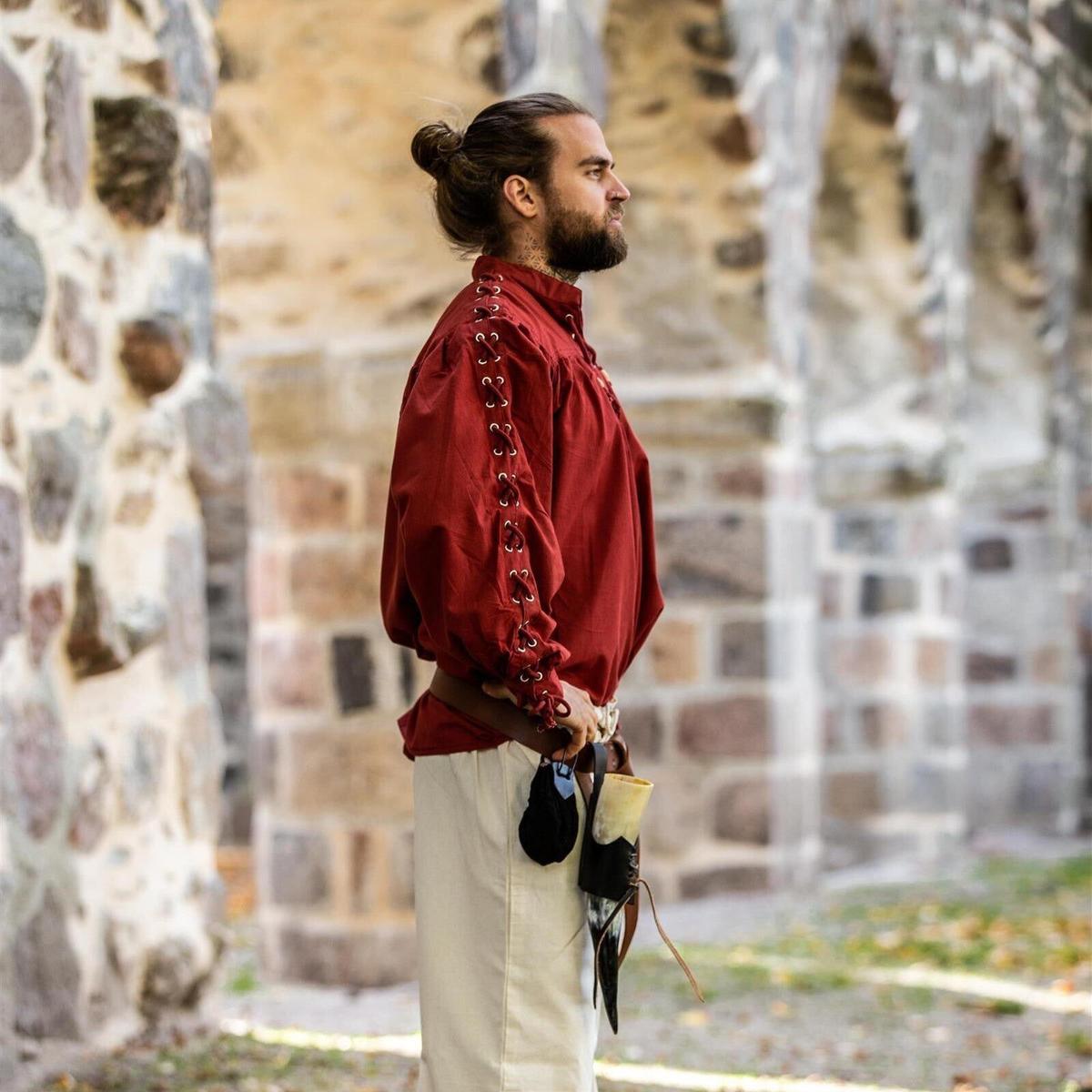 Red Pirate Shirt with adjustable lace-up sleeves, worn by a man with a beard and bun, standing by stone ruins.