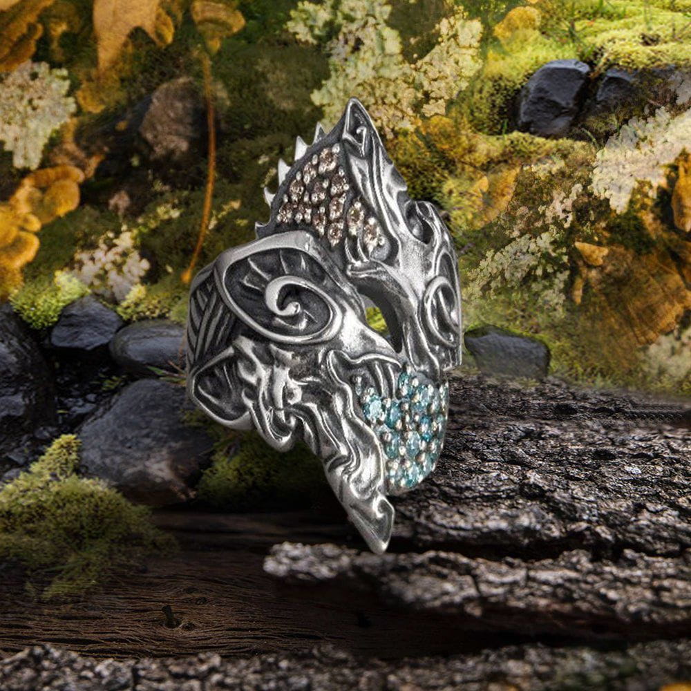 Sterling silver Pirate ring with twin wolf design, featuring brown and blue gemstones, on a mossy log.