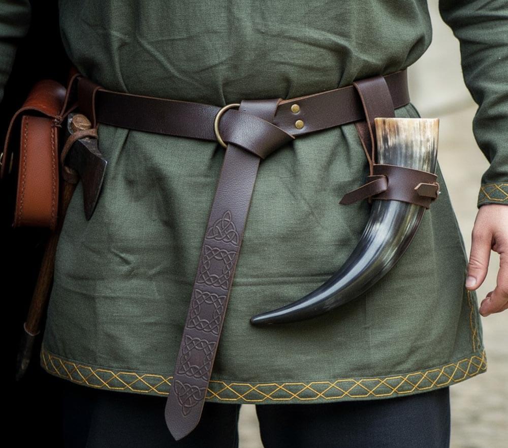 Person wearing a thick brown leather pirate belt with ring loop and knot on a green shirt with horned accessory.
