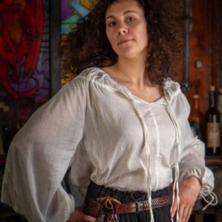 Woman in a white, loose-fitting crepe cotton Pirate shirt with drawstring neckline and wrists.