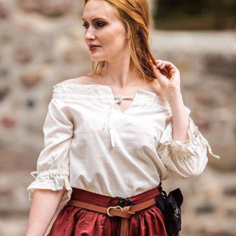 White cotton Pirate blouse with lace trim, worn off-shoulder, paired with a red skirt and brown belt.