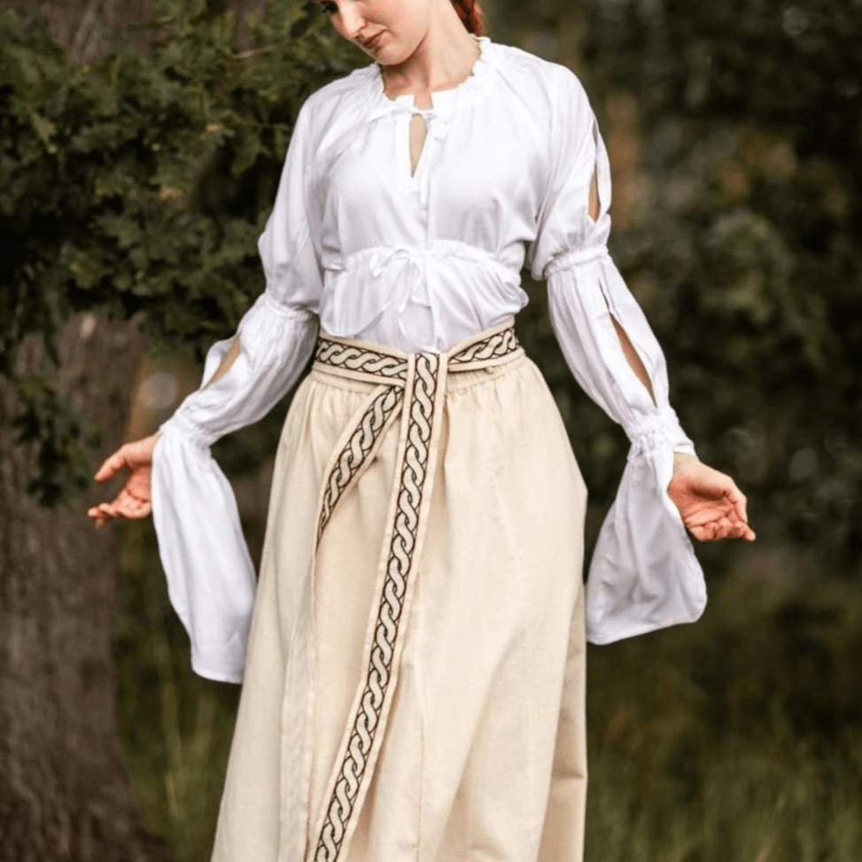 White long-sleeve Pirate blouse with ruched, split sleeves and adjustable waist lacing, worn with a skirt.