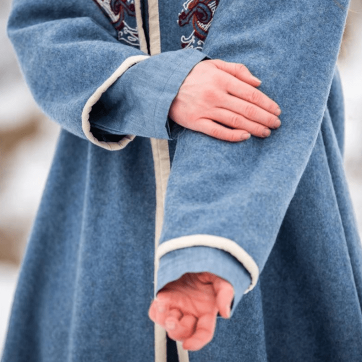 Close-up of hand embroidery on a blue wool coat