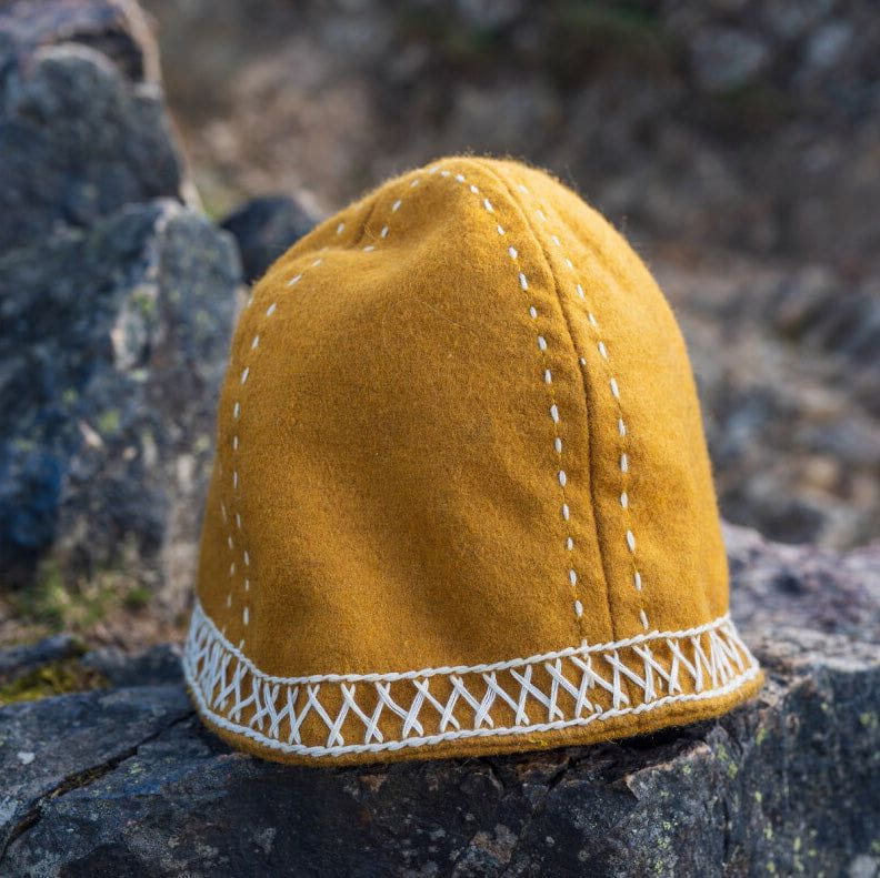 Model in costume wearing a mustard yellow wool cap with white embroidery