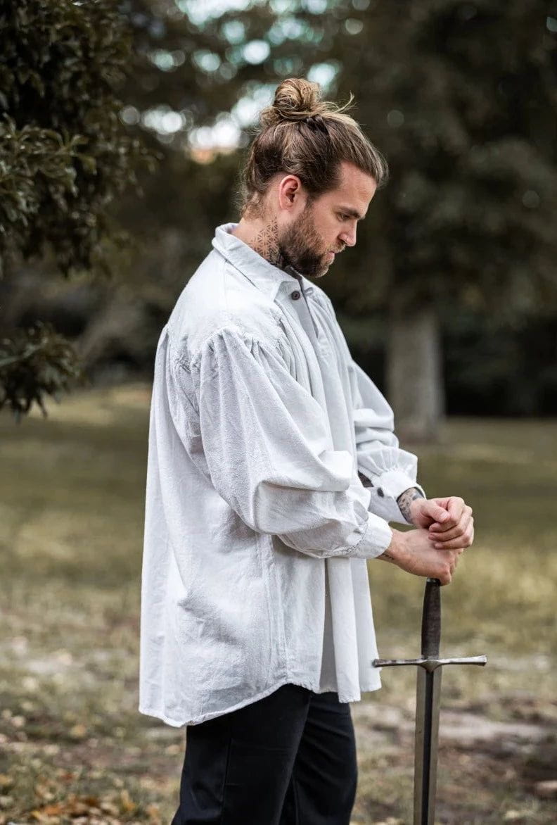 Man in a loose-fitting white cotton Pirate shirt with wooden buttons, holding a sword.