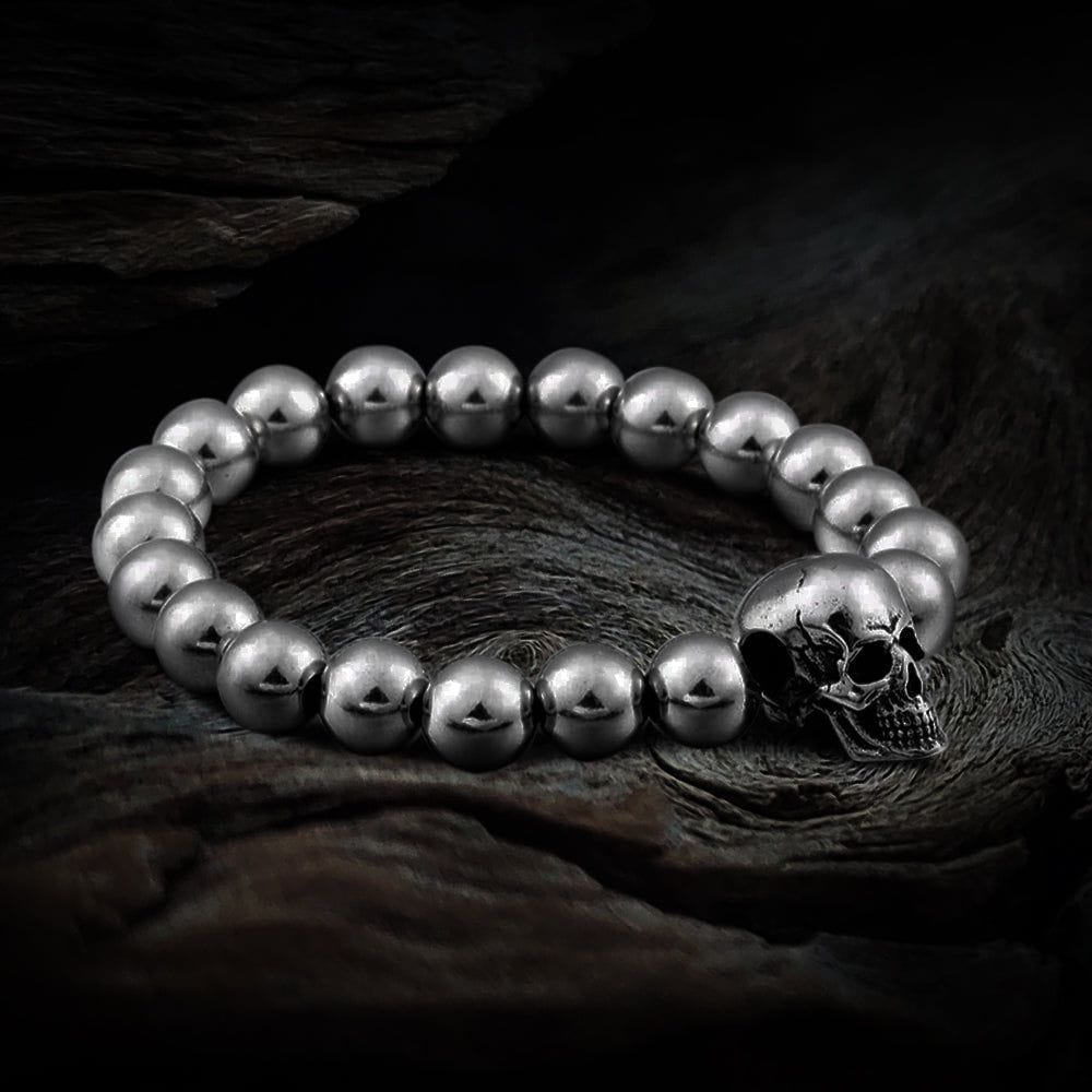 Polished stainless steel bead Pirate bracelet with a detailed skull charm on a dark wood surface.